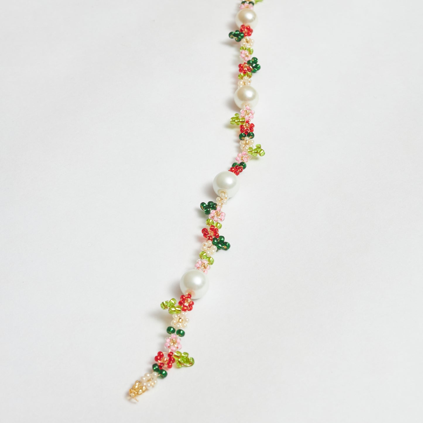 Collar estilo chocker con diseño de jardín floreado tejido a mano en mostacilla, muranos y rocaya en forma de flores en colores verde claro, verde oscuro, blanco, rosado, dorado y rojo.