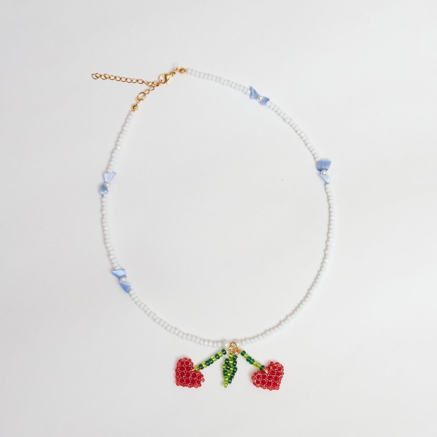 Collar tejido a mano en múranos, perlas Shell, piedras de cristal y mostacilla con un dije colgante en forma de cerezas de corazón, tejidas artesanalmente en colores verde claro, verde oscuro y rojo con alambre de oro golfi.