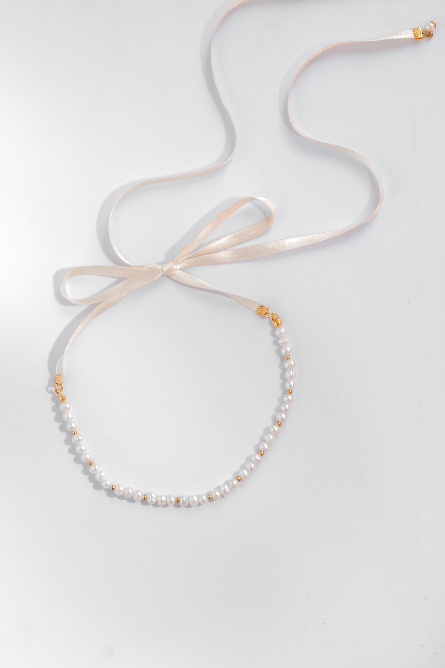 Collar estilo chocker hecho a mano con perlas de rio color blanco y cintilla color crema anudada con un moño