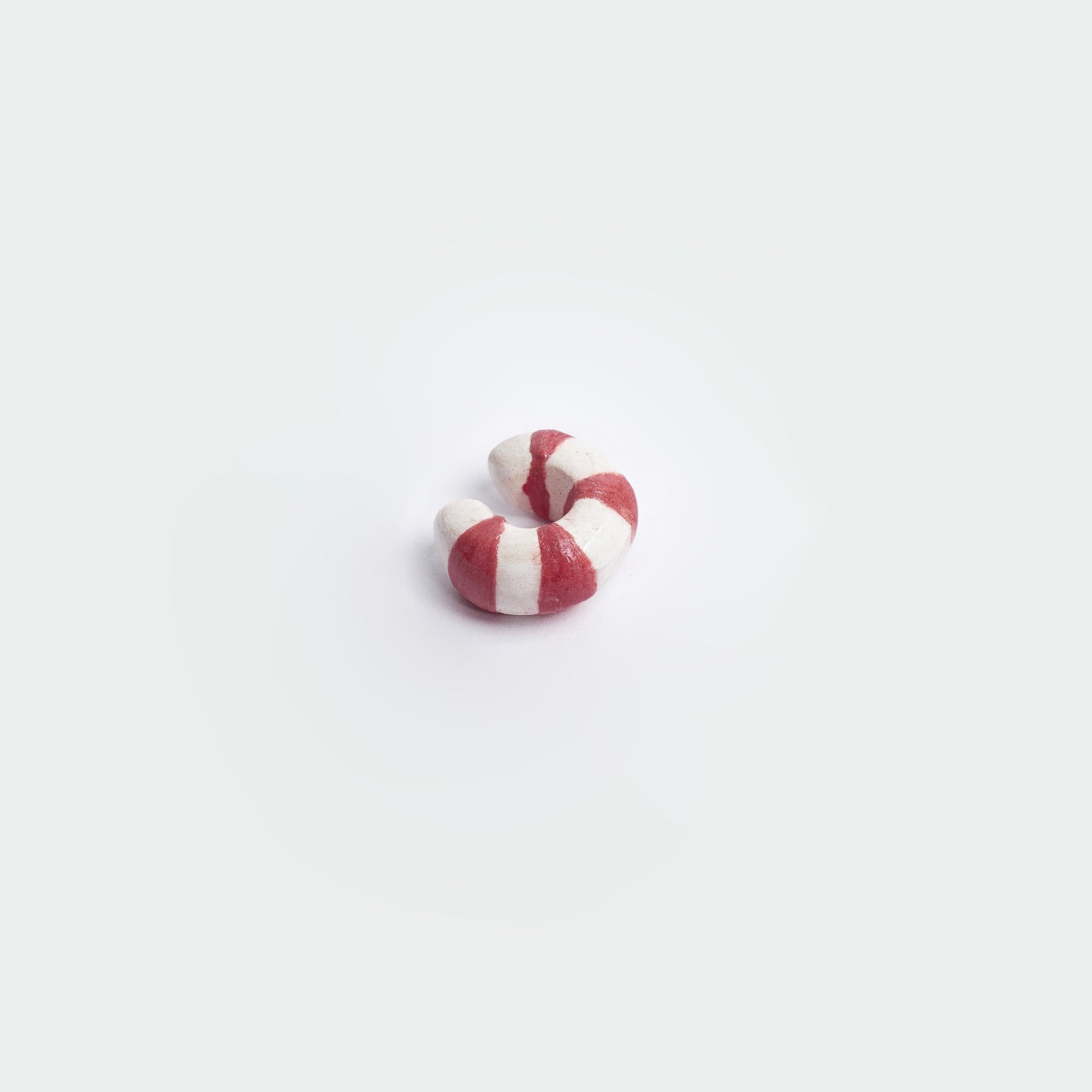 Earcuff en fondo blanco hecho a mano en material de cerámica con estilo a rayas en colores rojo y blanco