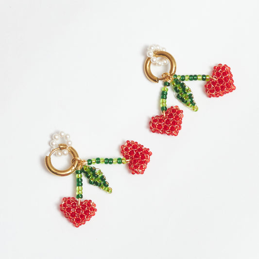 Aretes Berries estilo candonga en acero inoxidable color dorado con dijes en forma de cerezas tejidos artesanalmente con alambre de oro golfi en rocaya de colores verde claro, verde oscuro y rojo y dije circular de perlas.