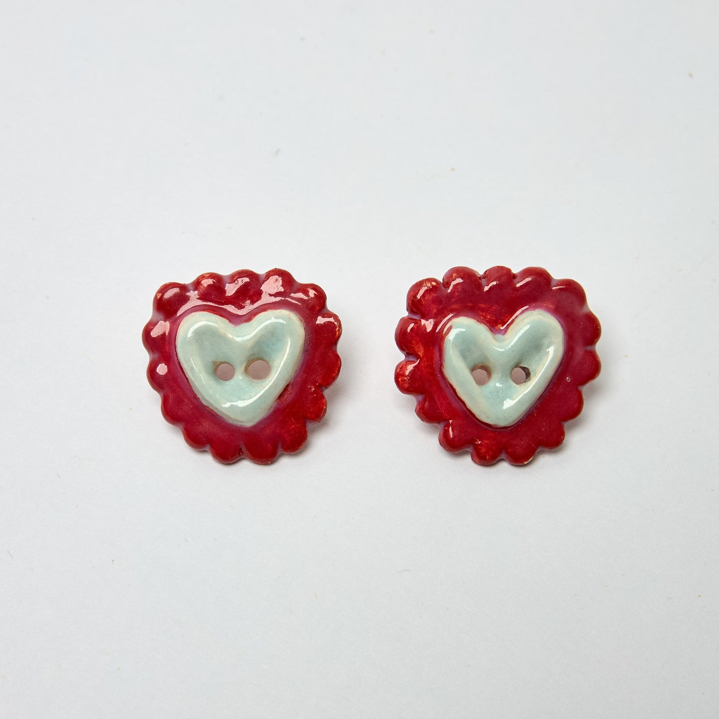 Aretes estilo pendiente en material de cerámica con forma de corazón de galleta en colores rojo y celeste pintados a mano
