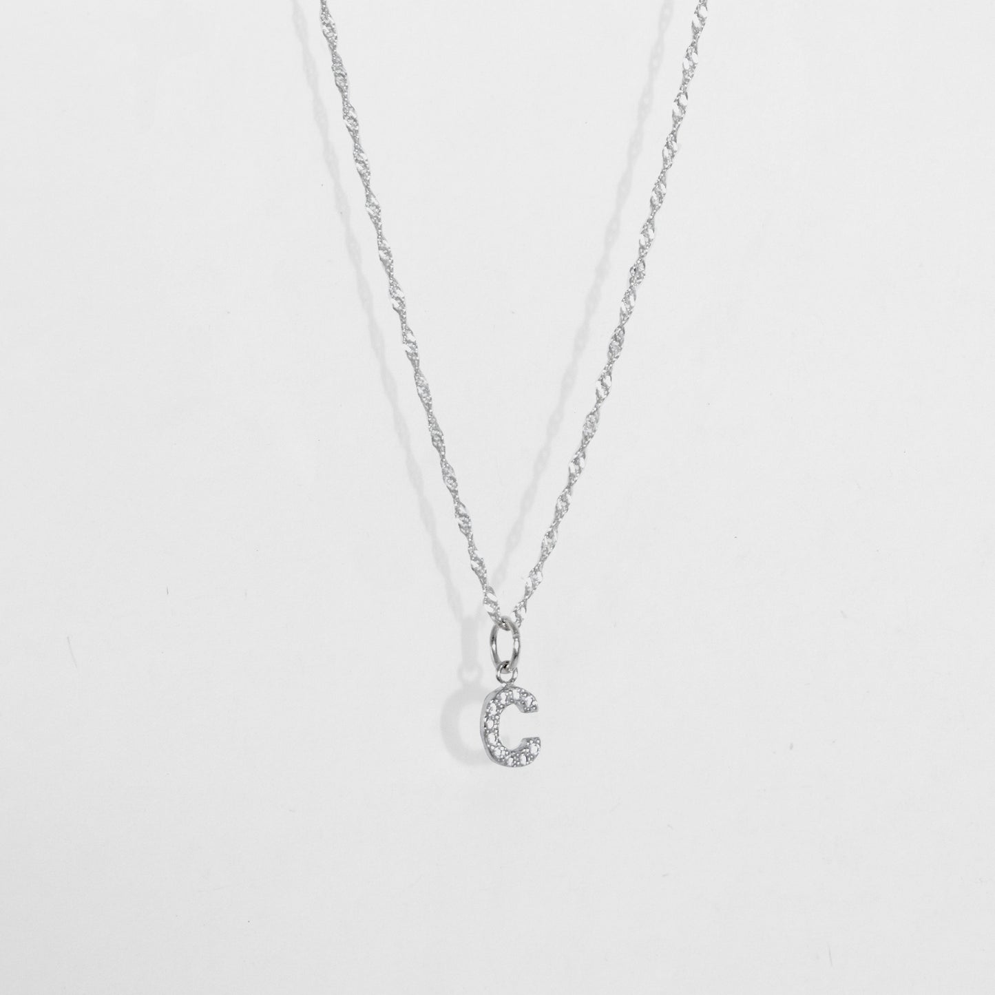 Cadena en material de plata ley 925 en tejido eslabón fino con dije de letra C con diamantes zircones incrustados.