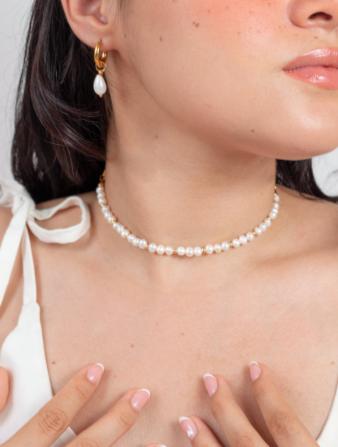 Cuello de modelo con collar estilo chocker  acompañado de pendientes y vestido color blanco