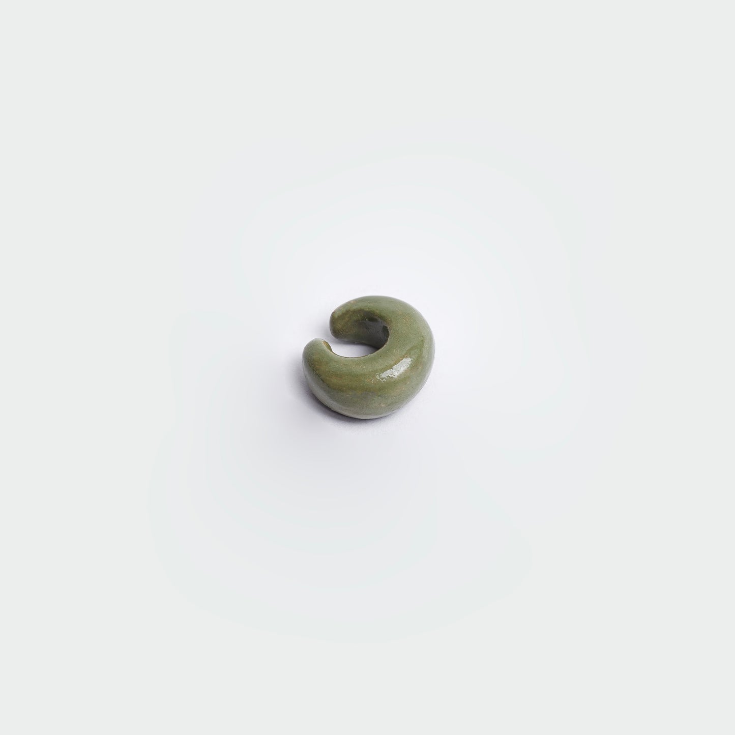 Earcuff en fondo blanco estilo clásico en color verde oscuro hecho en material de cerámica.