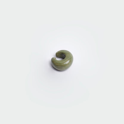 Earcuff en fondo blanco estilo clásico en color verde oscuro hecho en material de cerámica.
