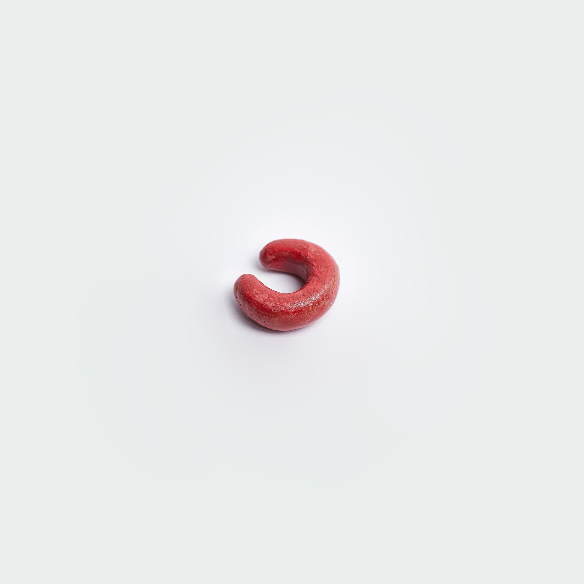 Earcuff en fondo blanco, estilo clásico en material de cerámica en color rojo. 