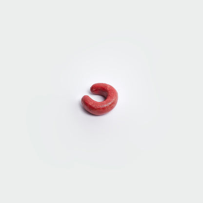 Earcuff en fondo blanco, estilo clásico en material de cerámica en color rojo. 