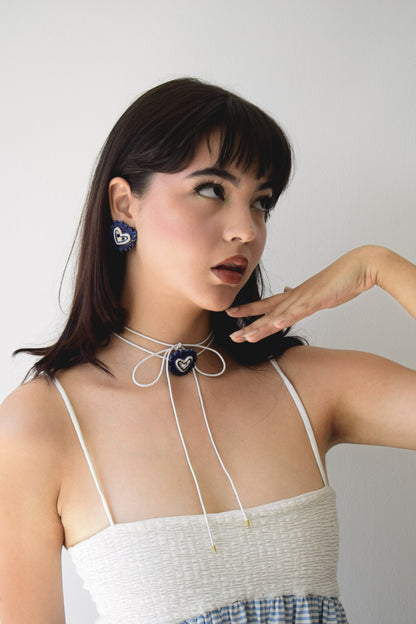 Modelo de tes blanca y cabello negro con vestido blanco y set La Galletera que incluye aretes y chocker la galletera con dijes de cerámica, foto tomada en fondo blanco